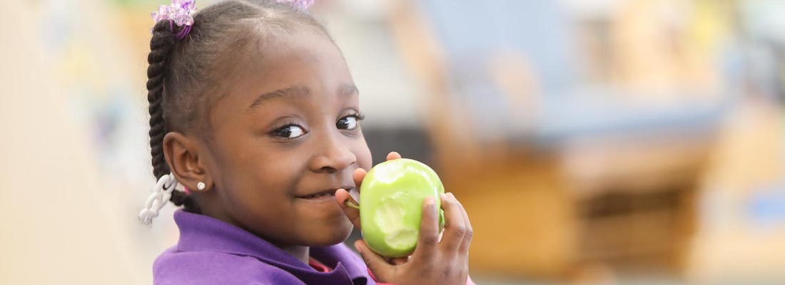 Student posing eating an apple in class