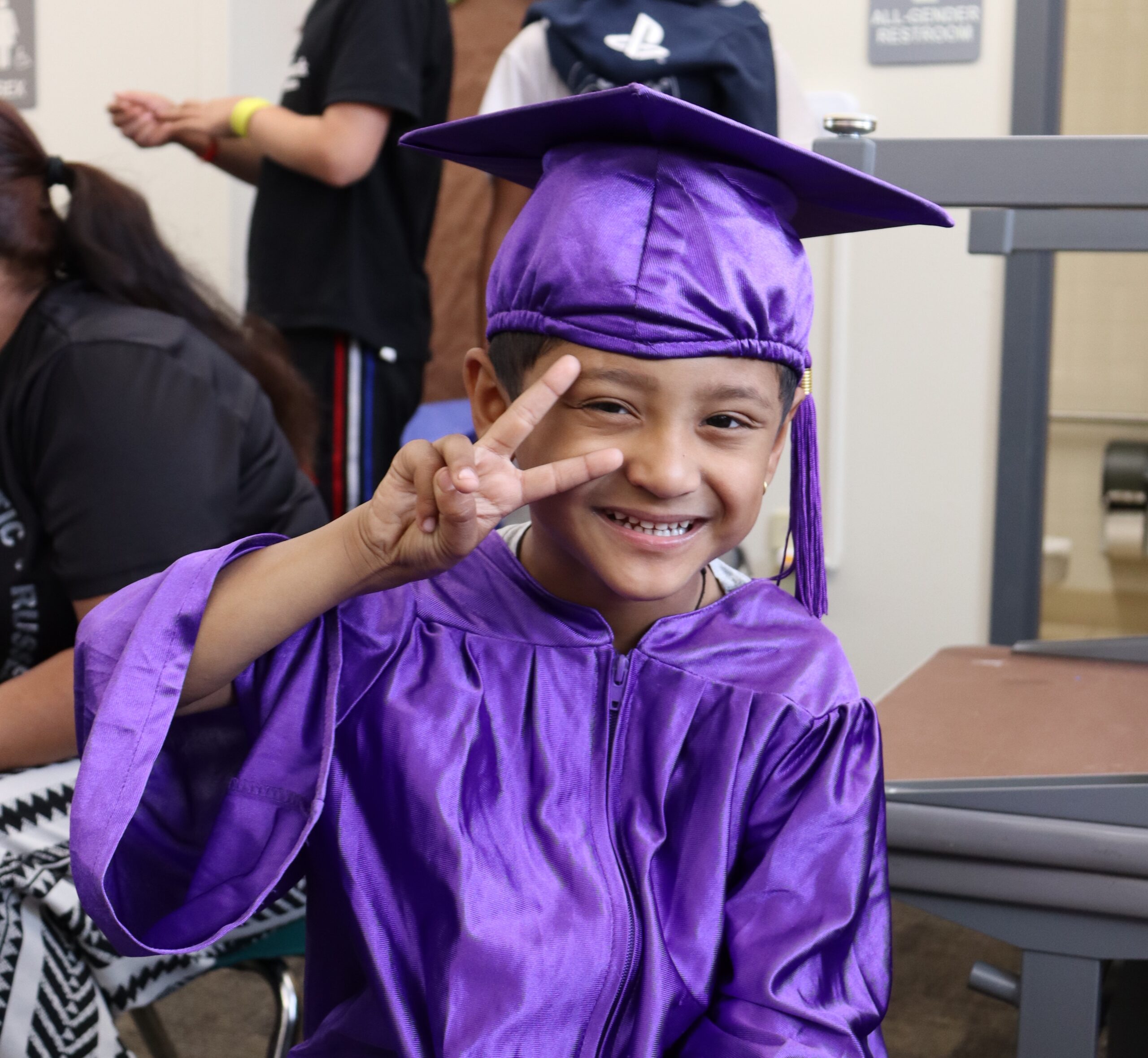 student in graduation attire holding peace sign